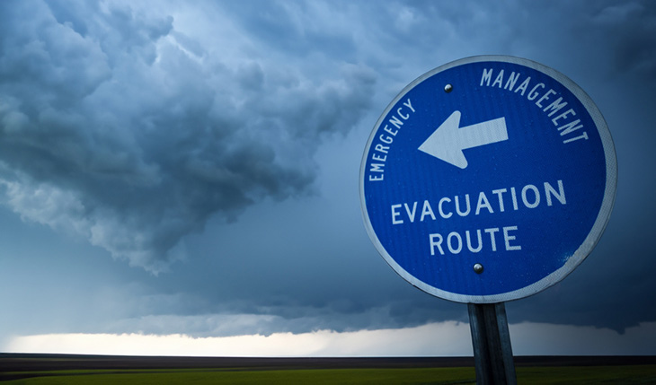 An emergency evacuation route road sign with a stormy sky in the background.