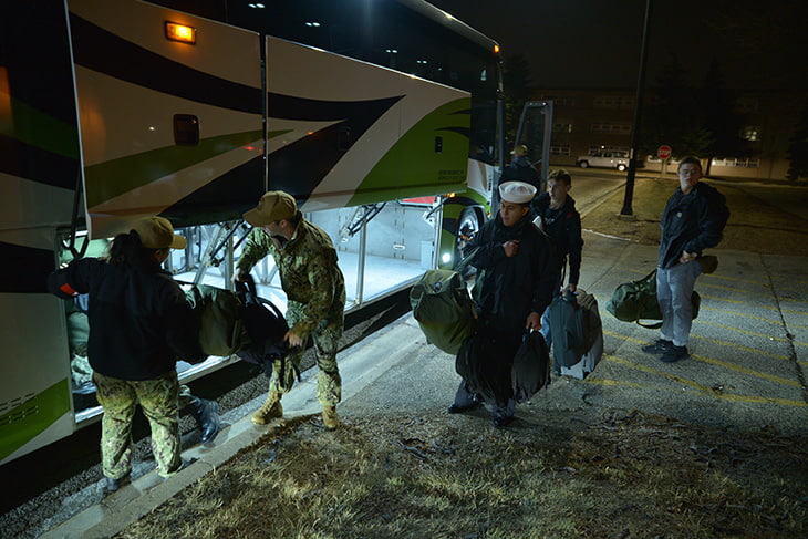 Sailors loading a charter bus rental with baggage.