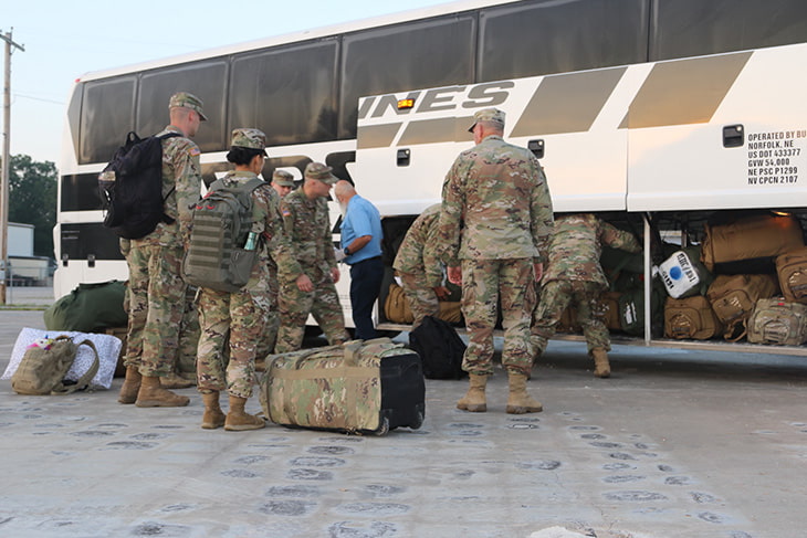 Soldiers loading a charter bus with baggage.