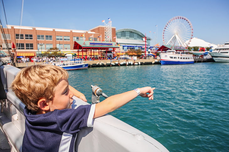 A small child pointing at the ferris wheel at Navy Pier.