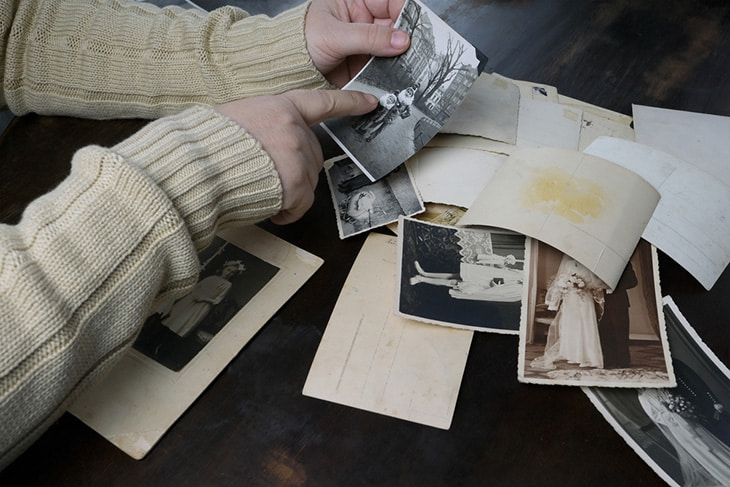 A woman looking at old photographs of family history.