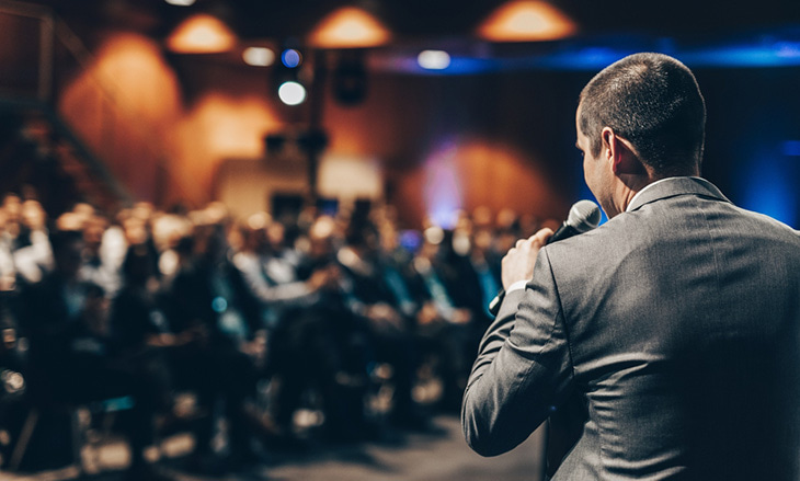 A keynote speaker at a conference addressing an audience.