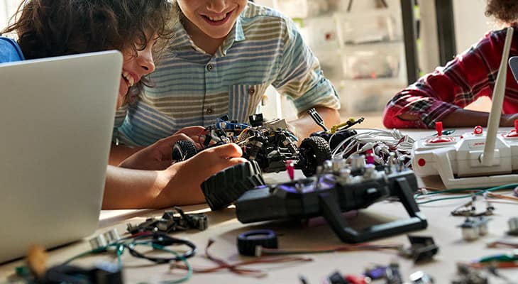 Children smile and work on a robotics project