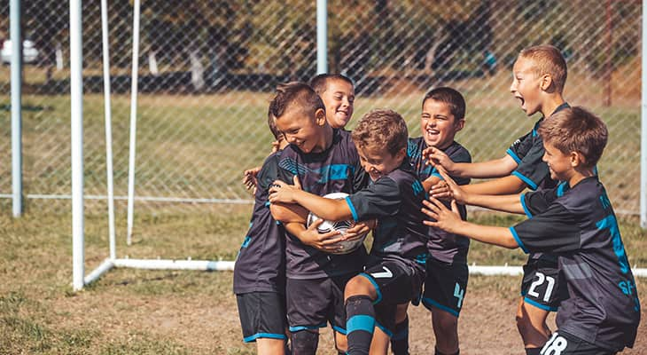 Young soccer players cheer and embrace in front of a goal