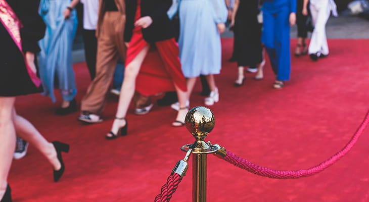 People in formal wear walk at a red carpet event