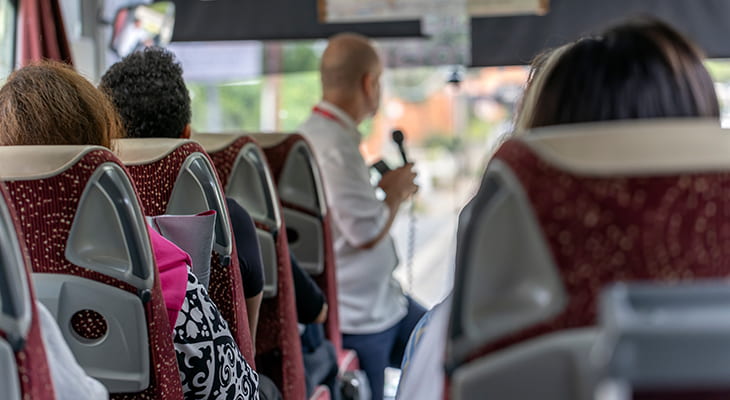 A tour guide speaks to tourists on a charter bus